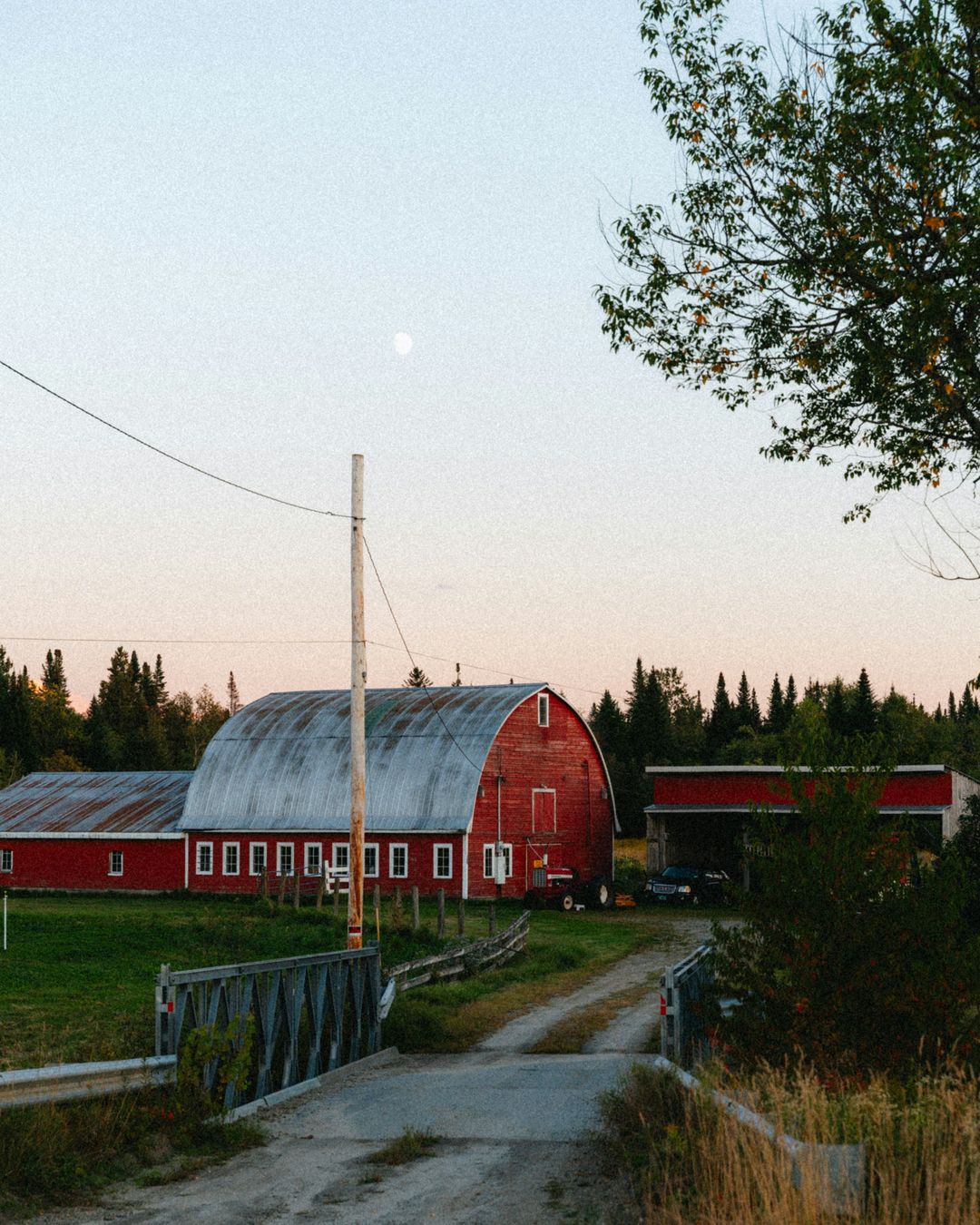 A red barn at dusk with the moon up, the time most crews have stopped answering the phone